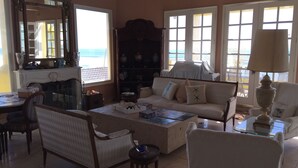 Ein großzügiges Wohnzimmer mit einer Couch, Sesseln, einem Couchtisch und einem Kamin.