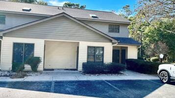 A two-story building with a garage, a covered driveway, and a parked car.