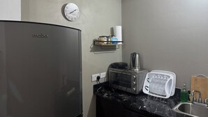 Una kitchenette equipada con refrigerador, microondas, tostadora y escurreplatos.