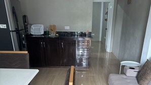 Una sala moderna con comedor, una cocina con armarios oscuros y un sofá gris.