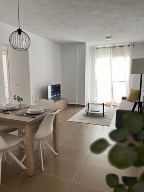 A modern living room with a dining area, a TV, and a sofa. - Central Málaga Apartment for 6 with Free HSWiFi & Parking, Steps from the Center (Málaga)