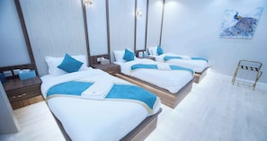 Three beds with wooden headboards and bedside tables offer a comfortable retreat.
