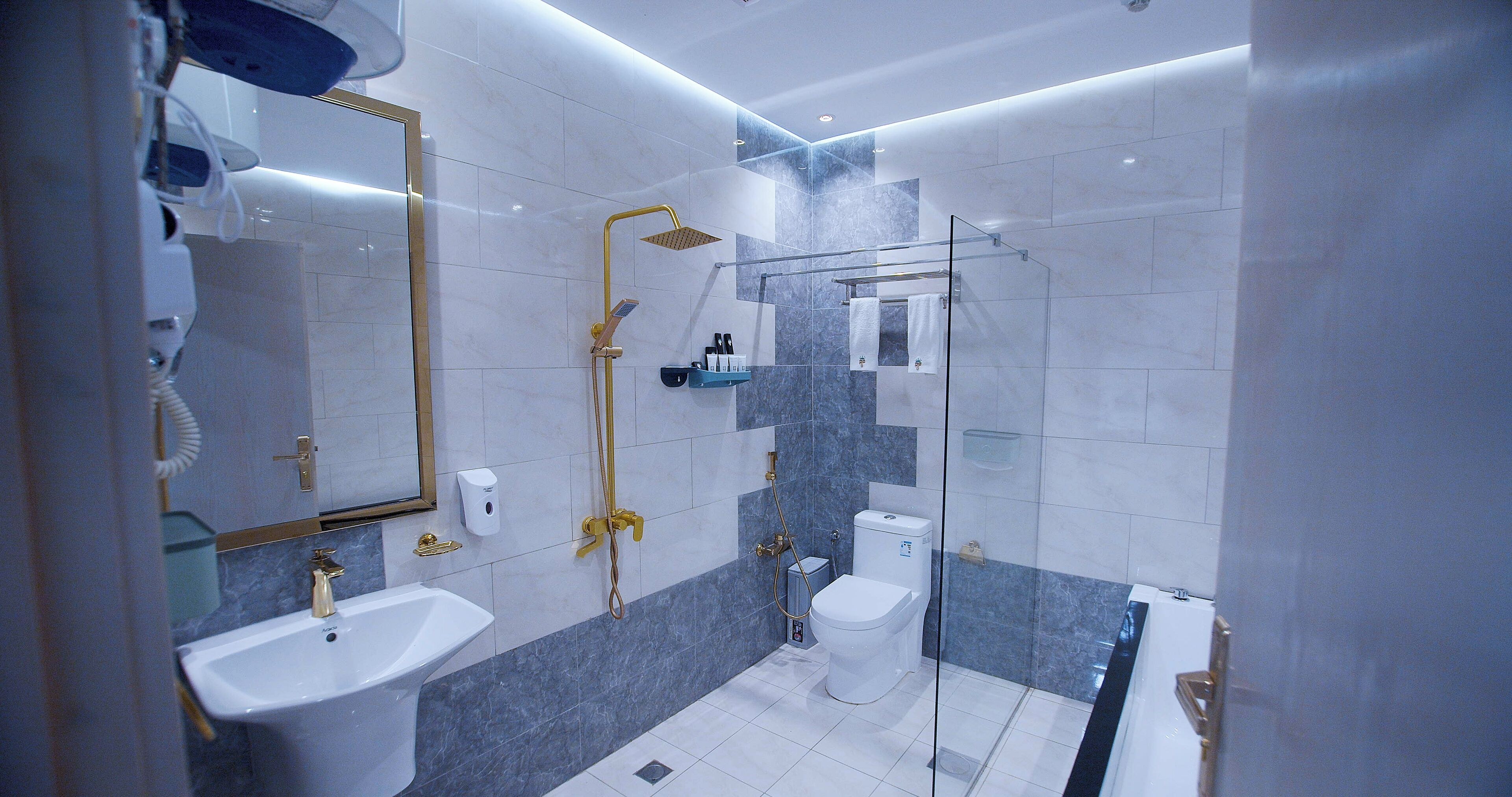 Un baño moderno con cabina de ducha de vidrio, un lavamanos blanco y un inodoro.