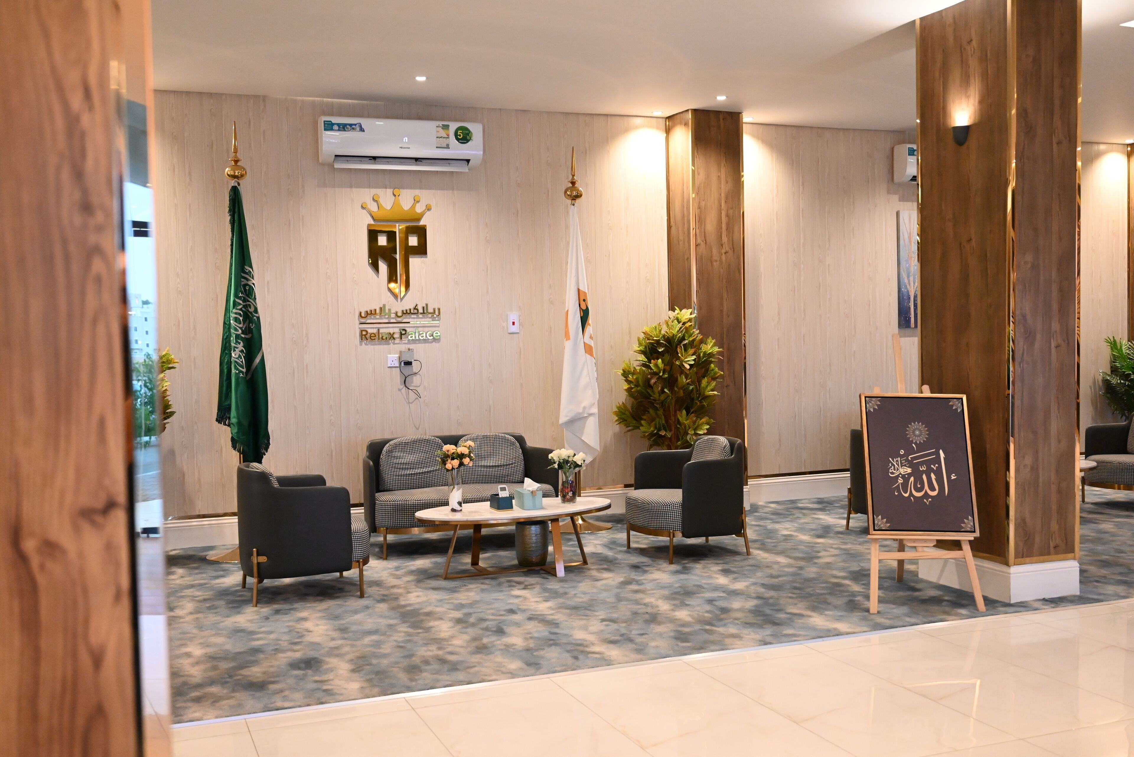 A lobby area with a reception desk, seating arrangement, and a signboard with Arabic script.