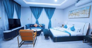Relax in a spacious room with a large bed, comfortable sofa, and mounted TV.