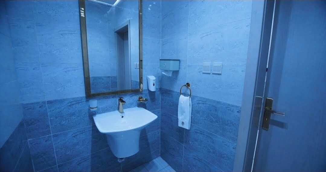Un baño con lavamanos, espejo, toallero y una puerta.