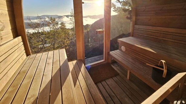 A wooden cabin with a bench and a table, a door leading outside, and a view of a mountainous landscape. - Wellness hut with panoramic view and home gym (Telemark)