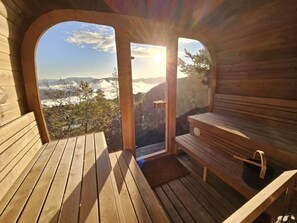 Una cabaña de madera con un banco y una mesa, una puerta que da al exterior y vistas a un paisaje montañoso.