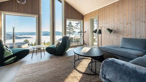 A spacious living room with large windows, a high ceiling, and a view of the mountains. - Wellness hut with panoramic view and home gym (Telemark)