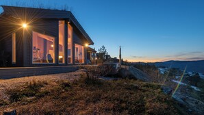 A modern house with large glass windows, a deck, and a view of the surrounding landscape. - Wellness hut with panoramic view and home gym (Telemark)