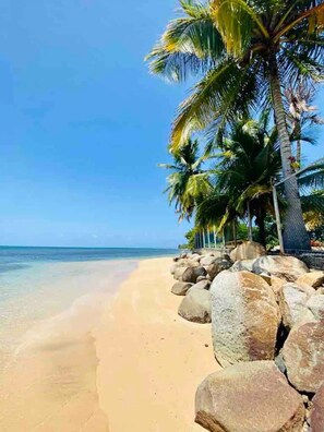 A beach with clear blue water, sandy shore, and large rocks. - New listing! Spacious 4-bedroom, water-front house in Las Picuas, Río Grande. (Río Grande)
