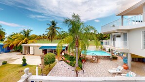 A hotel with a pool, outdoor seating, and a view of palm trees. - New listing! Spacious 4-bedroom, water-front house in Las Picuas, Río Grande. (Río Grande)