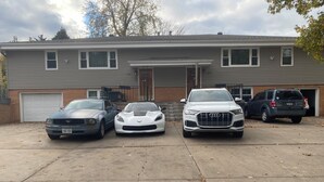 A two-story house with a garage and three parked cars. - Spacious Beautiful Omaha Retreat - 2BR/1BA Apartment with All-Inclusive (Omaha)