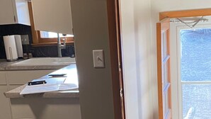 A kitchen with a countertop, a trash can, and a door leading to another room. - Spacious Beautiful Omaha Retreat - 2BR/1BA Apartment with All-Inclusive (Omaha)