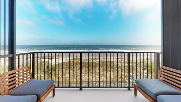 A balcony with a view of the beach and ocean. - Beachfront 2-bedroom condo with Gym, Pool, & WiFi, on  Jacksonville Beach. (Jacksonville Beach)