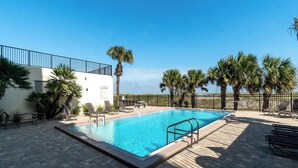A rectangular swimming pool with a no diving sign, surrounded by palm trees and lounge chairs, with a clear view of the ocean in the background. - Beachfront 2-bedroom condo with Gym, Pool, & WiFi, on  Jacksonville Beach. (Jacksonville Beach)