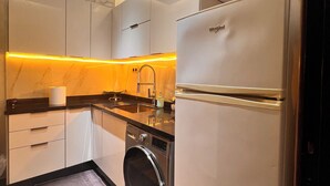 Une cuisine moderne dotée d’un lave-linge et d’un sèche-linge intégrés, d’appareils électroménagers en acier inoxydable et d’un pare-feu en marbre.