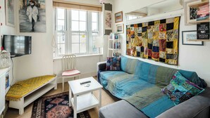 A cozy living room with a sofa, a small table, a chair, and a bookshelf.