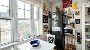 A compact kitchen with a white table, a black refrigerator, and a microwave.