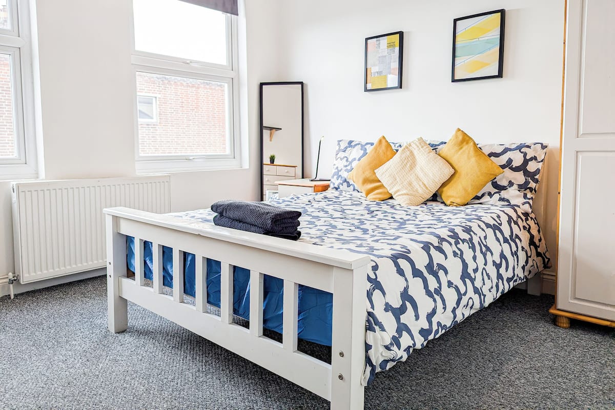 Un dormitorio con cama, radiador, ventana y puerta.
