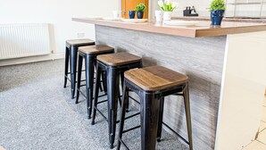 Een keuken met een houten aanrecht, vier zwarte barkrukken en potplanten.