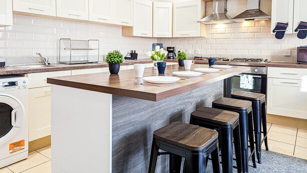 Een moderne keuken met een centraal eiland, inbouwapparatuur en een groot raam.
