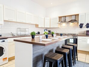 Una cocina moderna con una isla central, electrodomésticos integrados y un amplio ventanal.