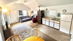 A compact living space with a kitchenette, a dining area with a table and chairs, a sofa, a ceiling fan, and a small kitchen island. - Keep it simple at this peaceful and centrally-located place.  (Polson)