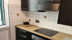 A modern kitchen with black cabinets, a stainless steel sink, and a wooden countertop. - Stella Polare Sensorial Home (Rome)