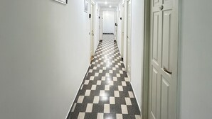 A hallway with a checkered floor, white walls, and doors on both sides. - Stella Polare Sensorial Home (Rome)