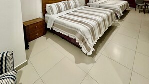 A bedroom with two beds, a small table, and a chair. - CASA ELIZABETH (Oaxaca)