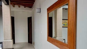 A hallway with a wooden ceiling, a large mirror, and a tiled floor. - CASA ELIZABETH (Oaxaca)