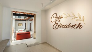 A modern interior with a hallway leading to a living area featuring a red sofa and a dining table. A decorative wall sign reads "Casa Elizabeth". - CASA ELIZABETH (Oaxaca)