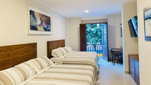 A hotel room with two beds, a painting on the wall, a TV, and a balcony with a view of trees. - CASA ELIZABETH (Oaxaca)