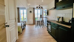 A modern kitchen with a dining area, wooden flooring, and a view of the city.