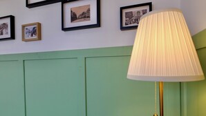 A room with a wooden table, a lamp, and a wall decorated with framed black and white photographs.