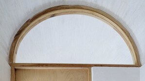 Een houten deur met een messing knop en een witte muur met een ronde lichtschakelaar.