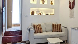 Een woonkamer met een bank, salontafel, een kamerbreed tapijt en wandplanken met decoratieve objecten.
