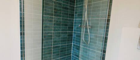 Een douche met glazen wanden, blauwe tegels en een wit toilet.