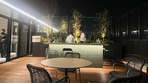 An outdoor dining area with a round table and chairs, a bar counter, and a view of the street. - Modern studio close to Allianz (Pompeia São Paulo)