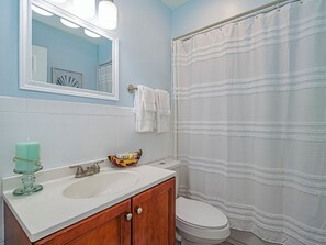 Ein Badezimmer mit Waschbecken, Spiegel, Toilette und Duschvorhang.