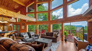 A spacious living area with large windows, wooden beams, and leather furniture.