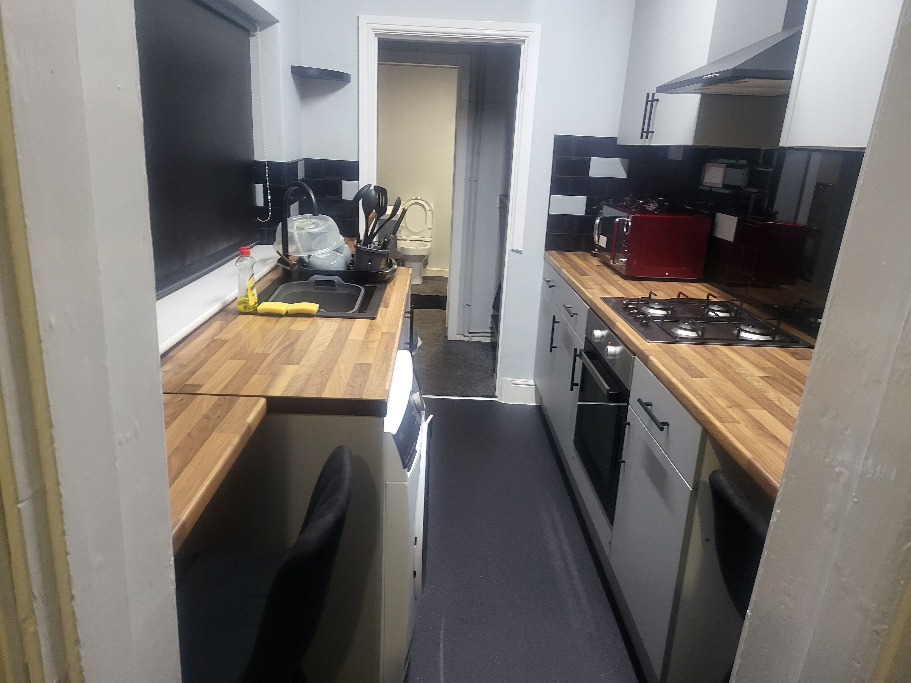 A compact kitchen with a wooden countertop, a sink, a stove, and a microwave.
