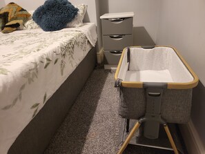 A baby changing station with a grey and white fabric design, a wooden frame, and a grey base.