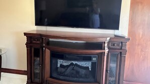 A flat-screen TV mounted on a wooden cabinet with a built-in fireplace below it. -  1 bedroom guest house in quiet, gated community. (Poway)