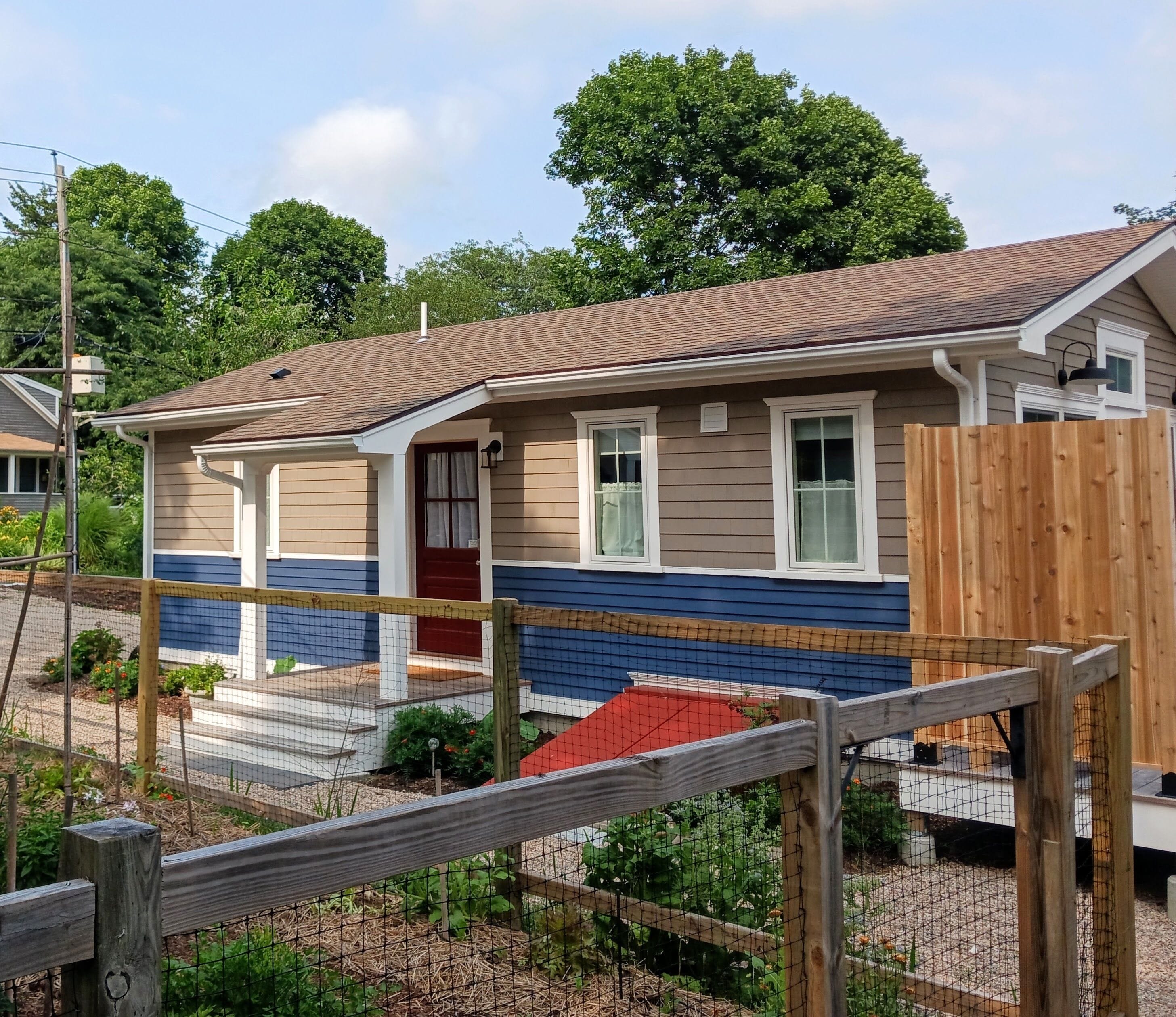 A two-story house with a red door, beige siding, and a blue trim.