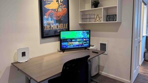 Un espace de bureau moderne comprenant un bureau, une chaise, un écran d’ordinateur et une affiche encadrée accrochée au mur.