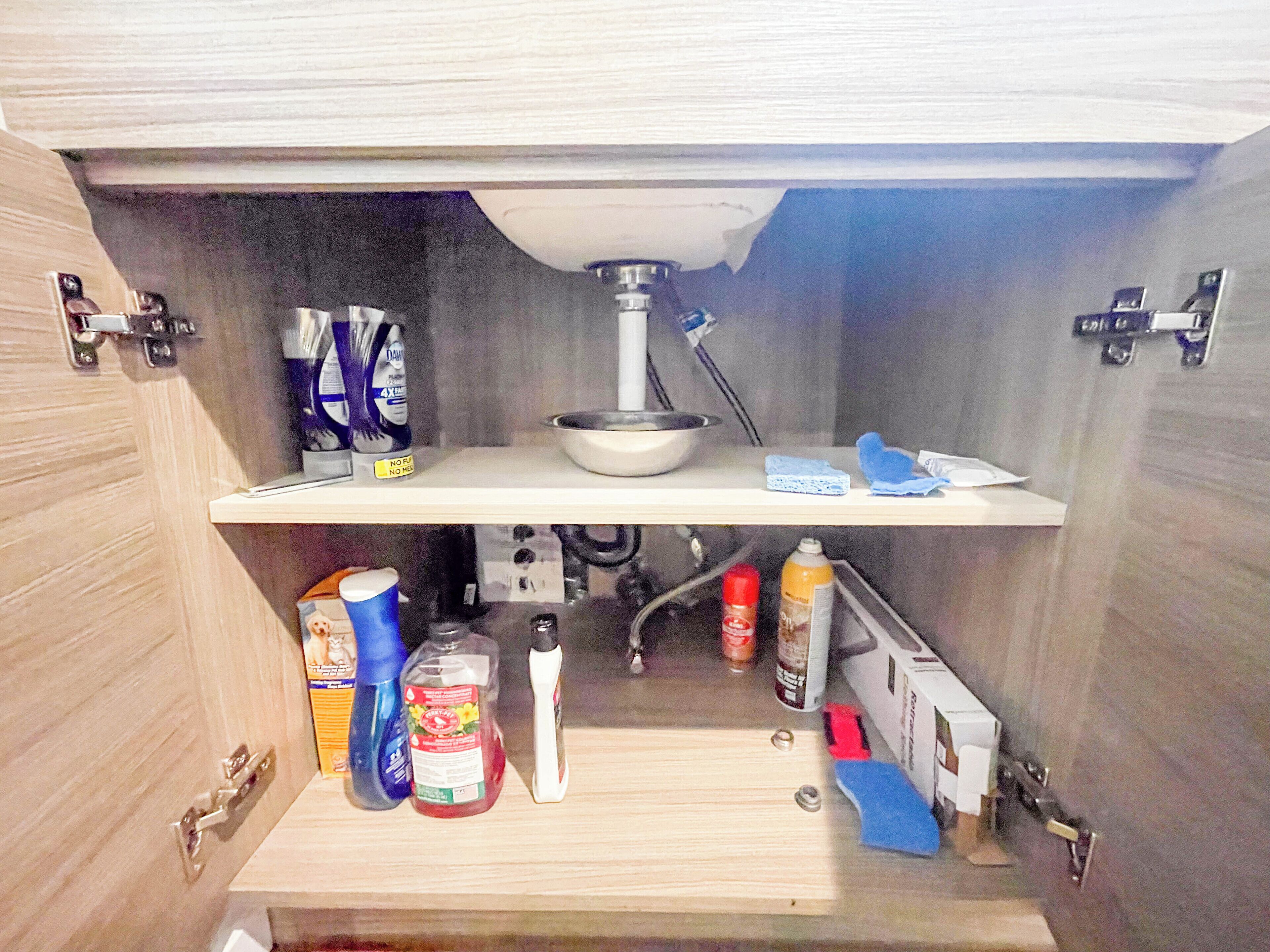 A kitchen with a wooden countertop, a sink, and various cleaning supplies.