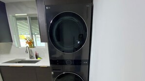 Una cocina moderna con lavadora y secadora integradas, un lavamanos con grifo y un cubo de basura.