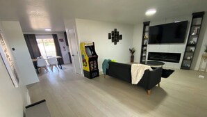 Una sala de estar con un sofá negro, un televisor y una consola de videojuegos.